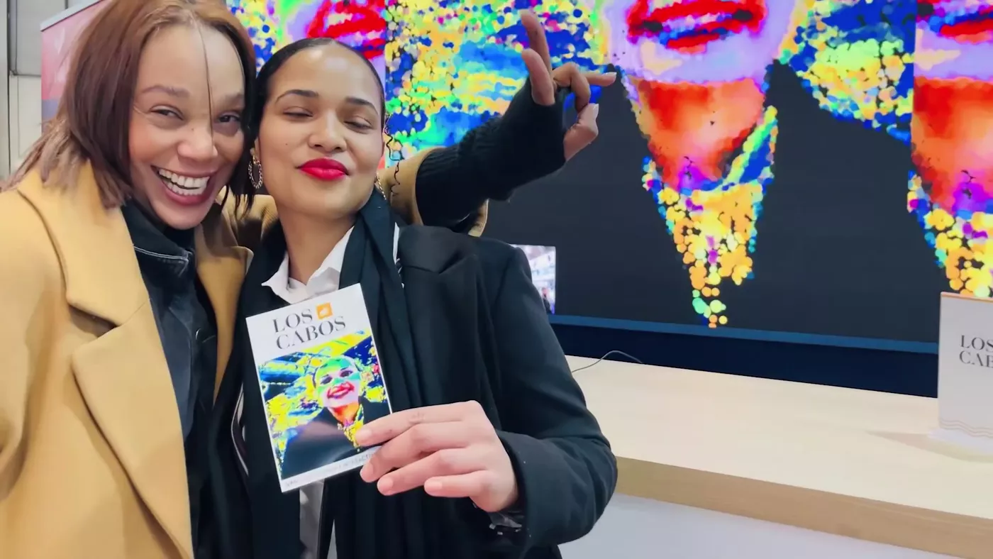 Two visitors laughing while holding their printed portraits at FITUR