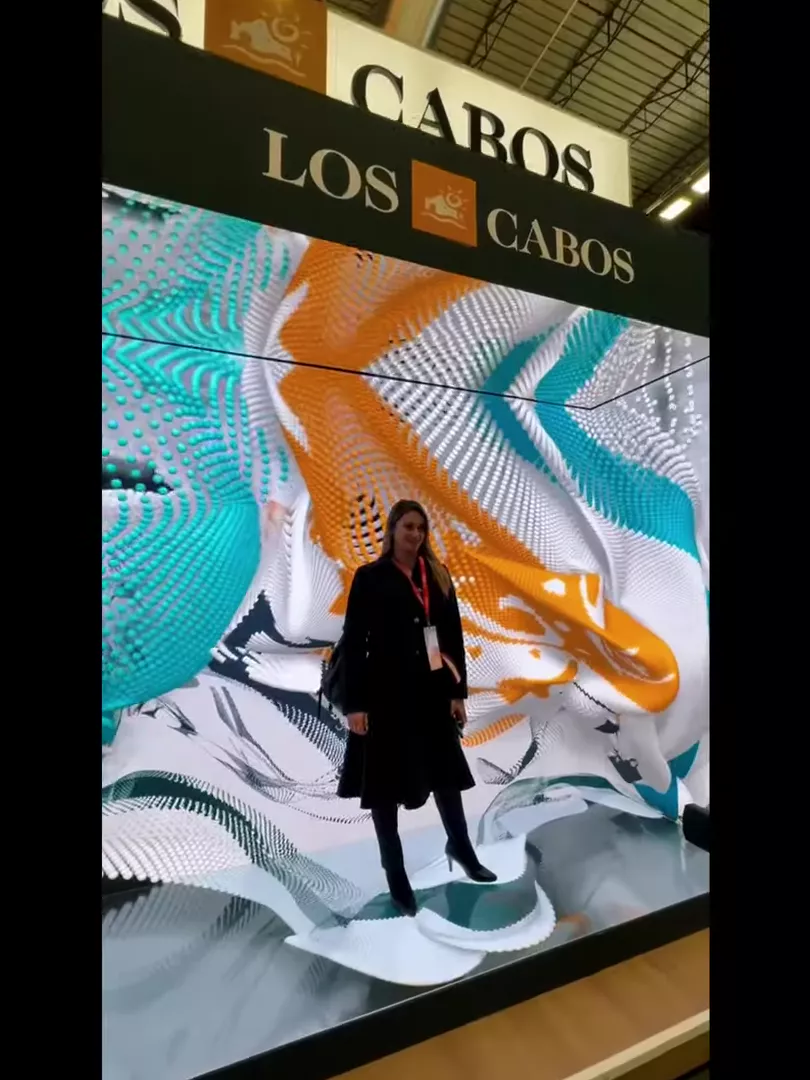 Visitor standing on an anamorphic LED floor wave in front of the kaleidoscope wall